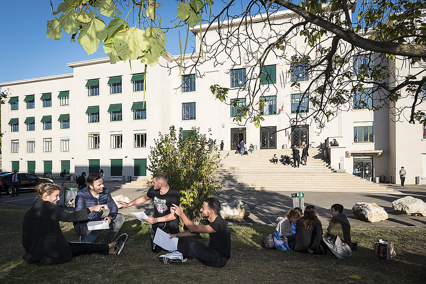 Des étudiants travaillent dans l'herbe devant le bâtiment universitaire Rockefeller 